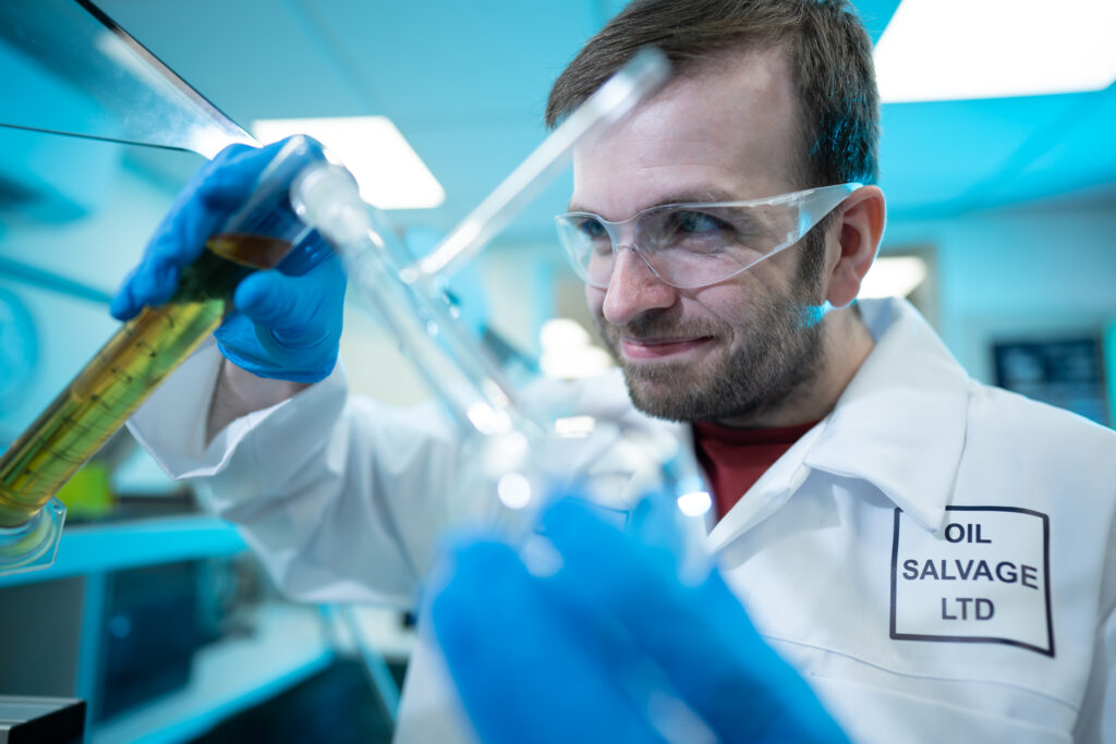 Lab manager Ian pouring a test tube of golden liquid into another container